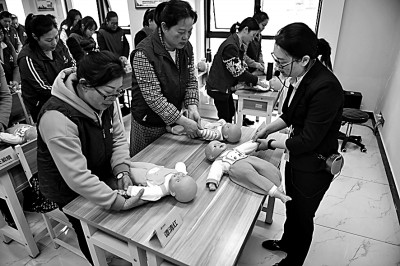 湖南长沙市的职业培训学校老师在育婴员培训班上为学员们讲解抚触婴儿的手法及注意事项。   新华社发